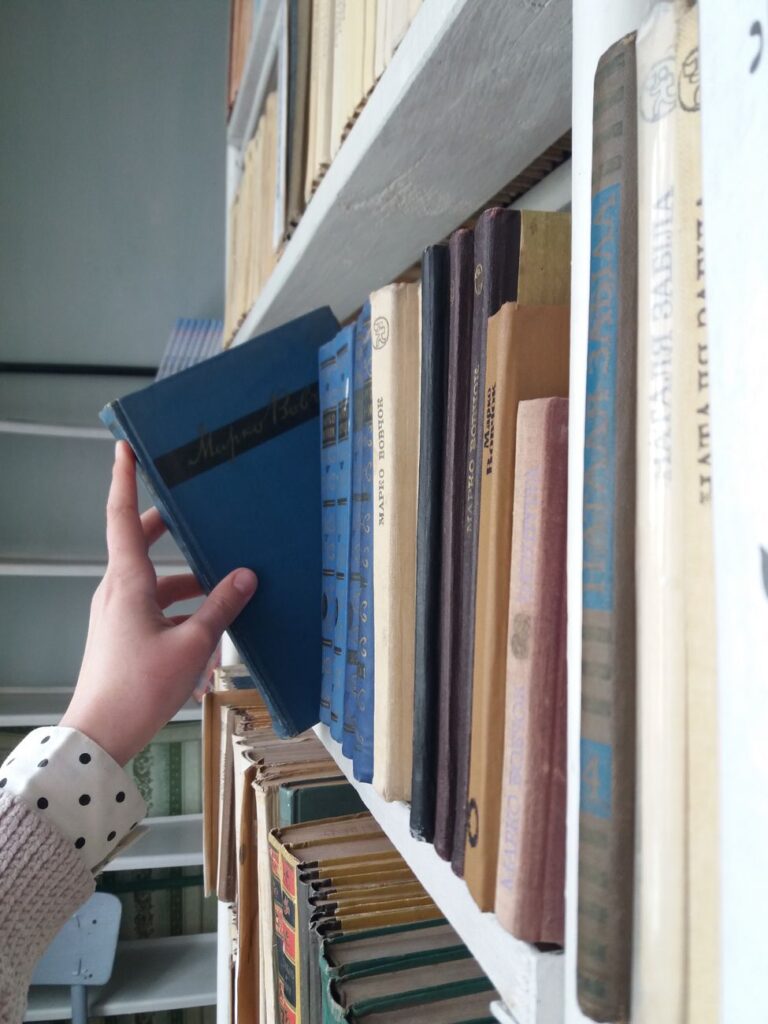 a hand getting the book form the wooden shelf