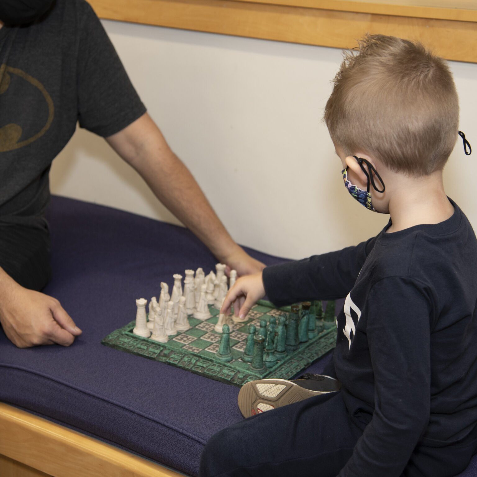 Child playing chess with an adult in the children's room