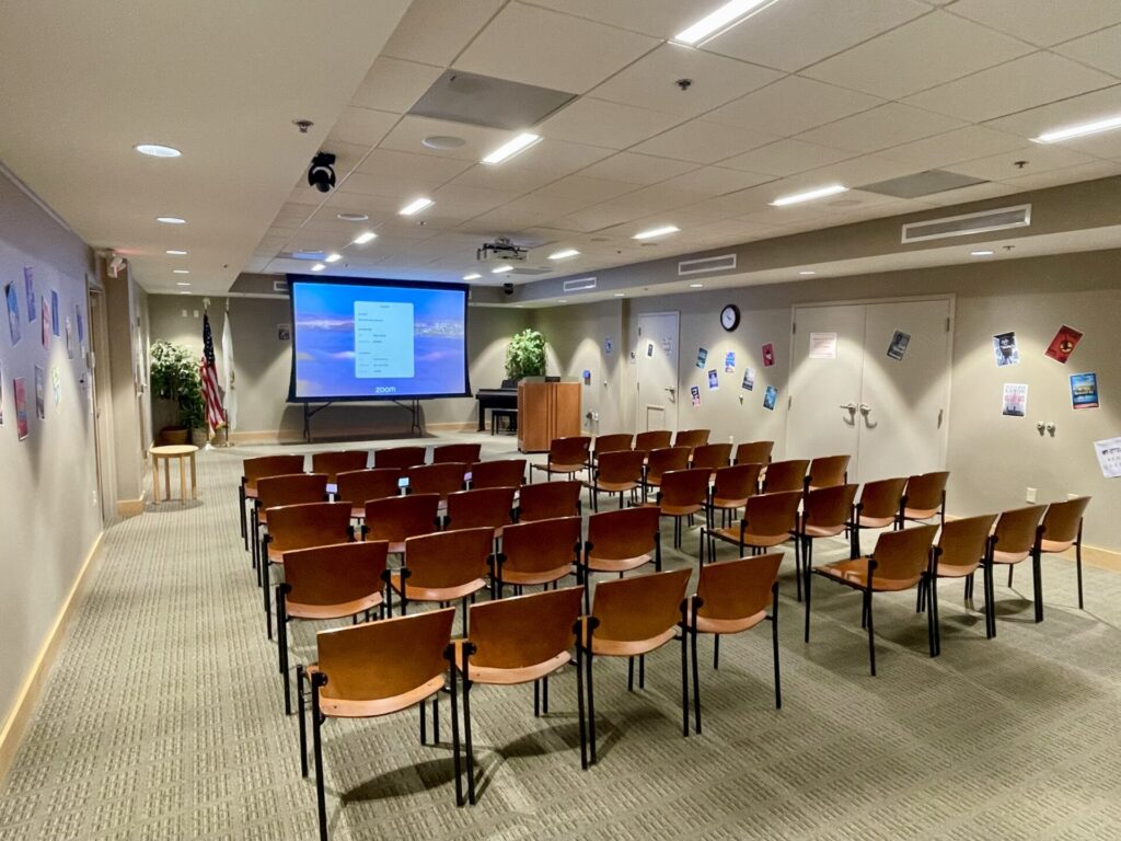 photograph of the Herreshoff Community Room overlooking the back of the chairs and facing the projection.